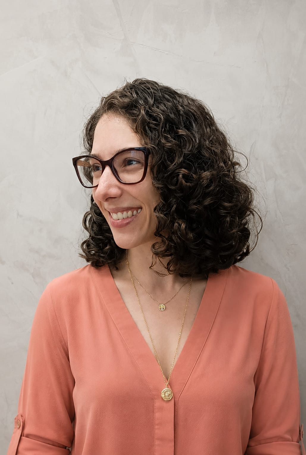 Lígia Zaiden de perfil, sorrindo, com blusa rosada